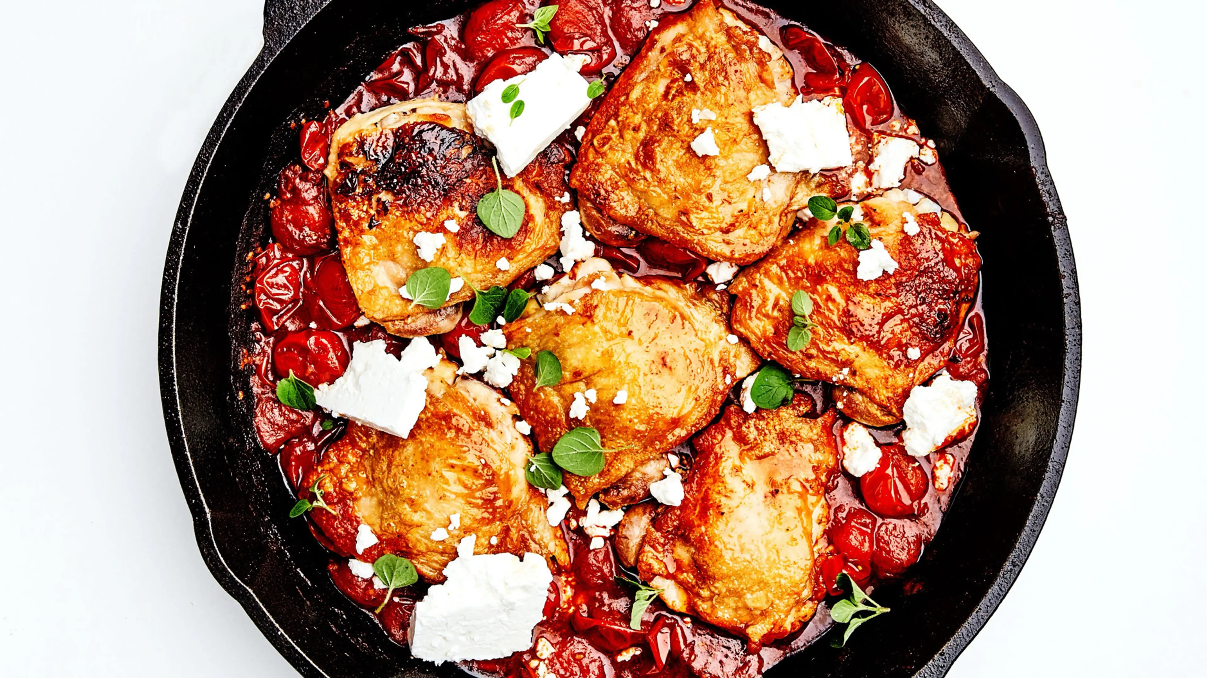 Chicken Thighs With Burst Tomatoes, Harissa, and Feta